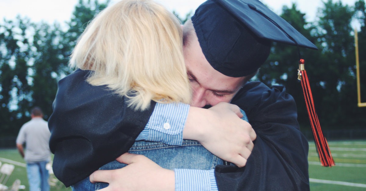 Graduate hugging woman