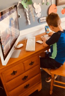 CCSD student doing homework while on a video call with his teacher.